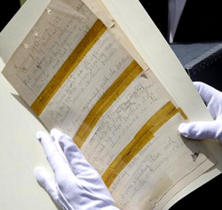 Gladys Ann Wells, Director, Arizona State Library, Archives and Public Records, uses gloves to show off a page of original court transcripts from the 1881 Coroner's Inquest in the Gunfight at the OK Corral on Wednesday. Photo by Ross D. Franklin