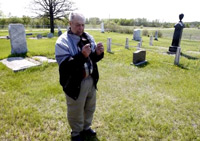 Jack Mavins uses welding rods to search for unmarked graves at an old cemetery near Dugald.