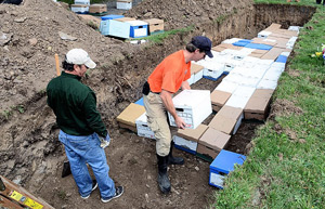 Daniel Seib, project director for Public Archaeology Facility at Binghamton University, is placing a box of remains from the Onondaga Poorhouse. Tom Roehm, with Onondaga County Parks, is helping place 80 bodies that were dug up during renovations at the former Onondaga Poorhouse and are being reburied at Loomis Hill Cemetery. Photo by Ellen M. Blalock / The Post-Standard